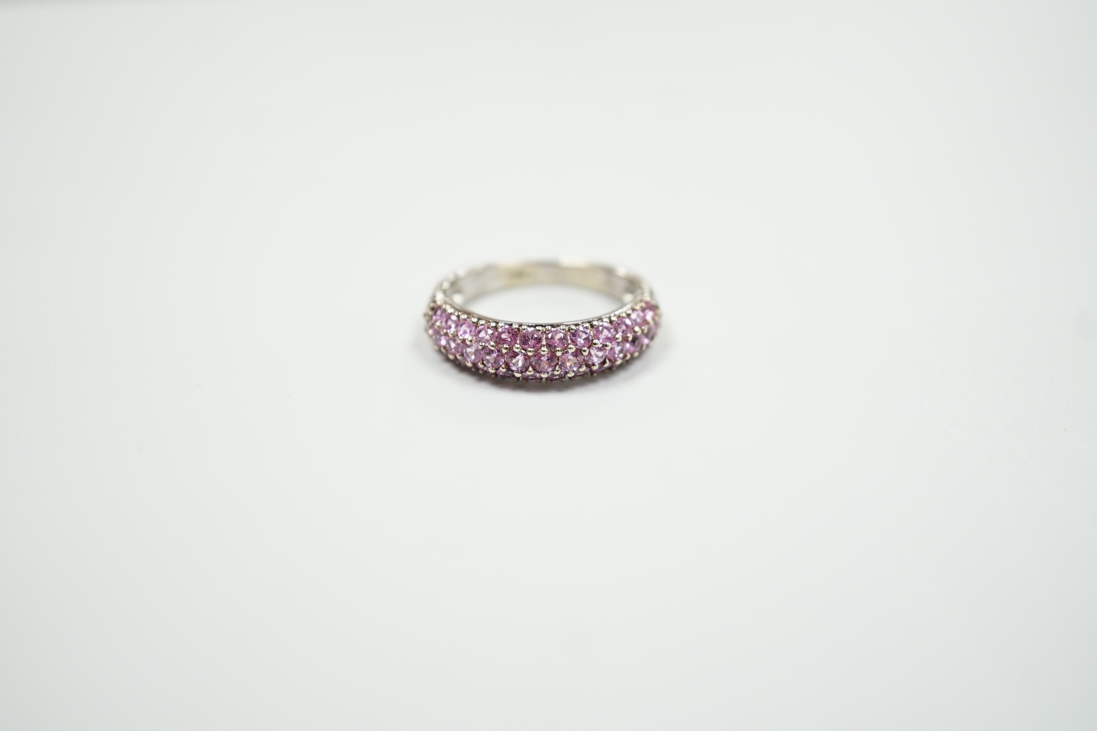 A modern 18ct white gold and pink stone cluster set half hoop ring, size J, gross weight 4.2 grams.